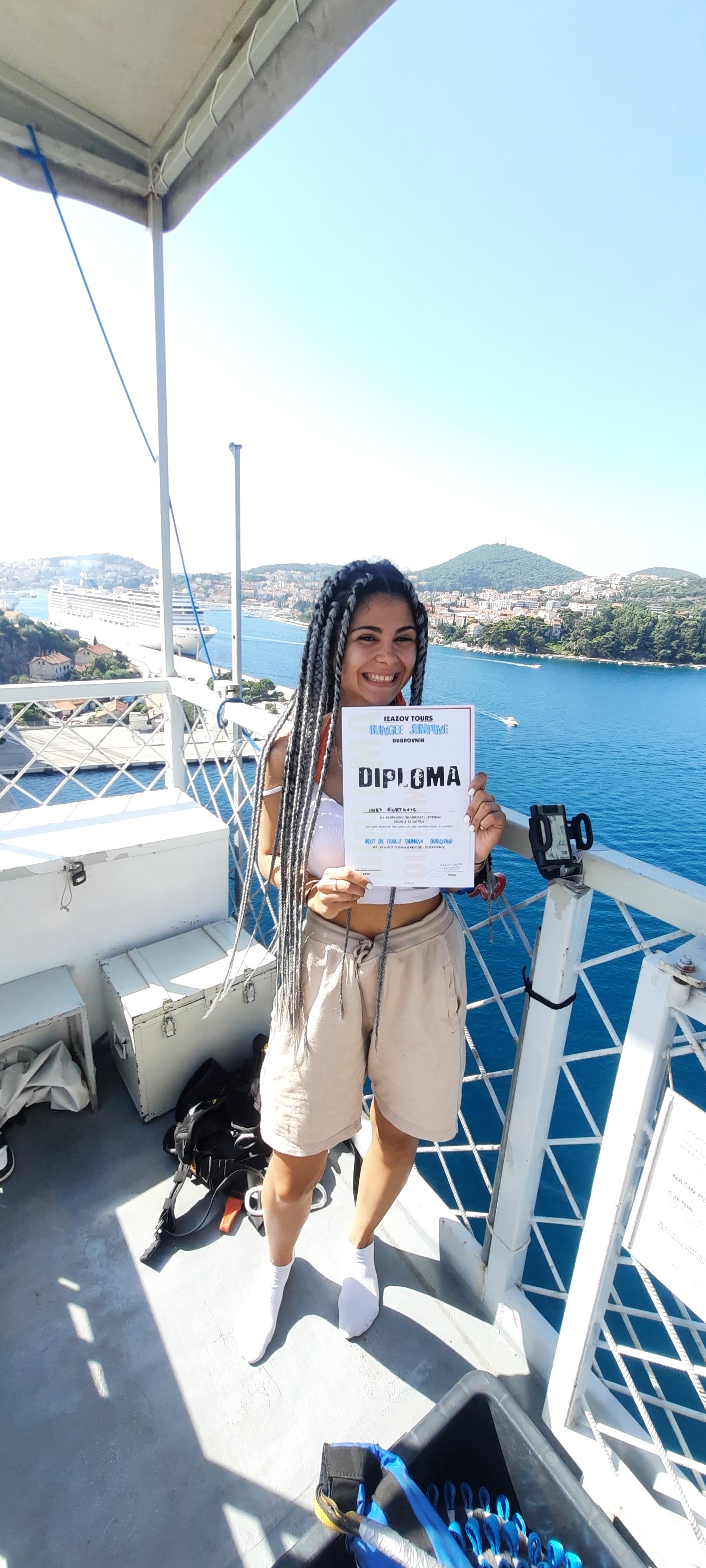 Participant proudly displaying a Dubrovnik Bungee Jump diploma with sea views in the background