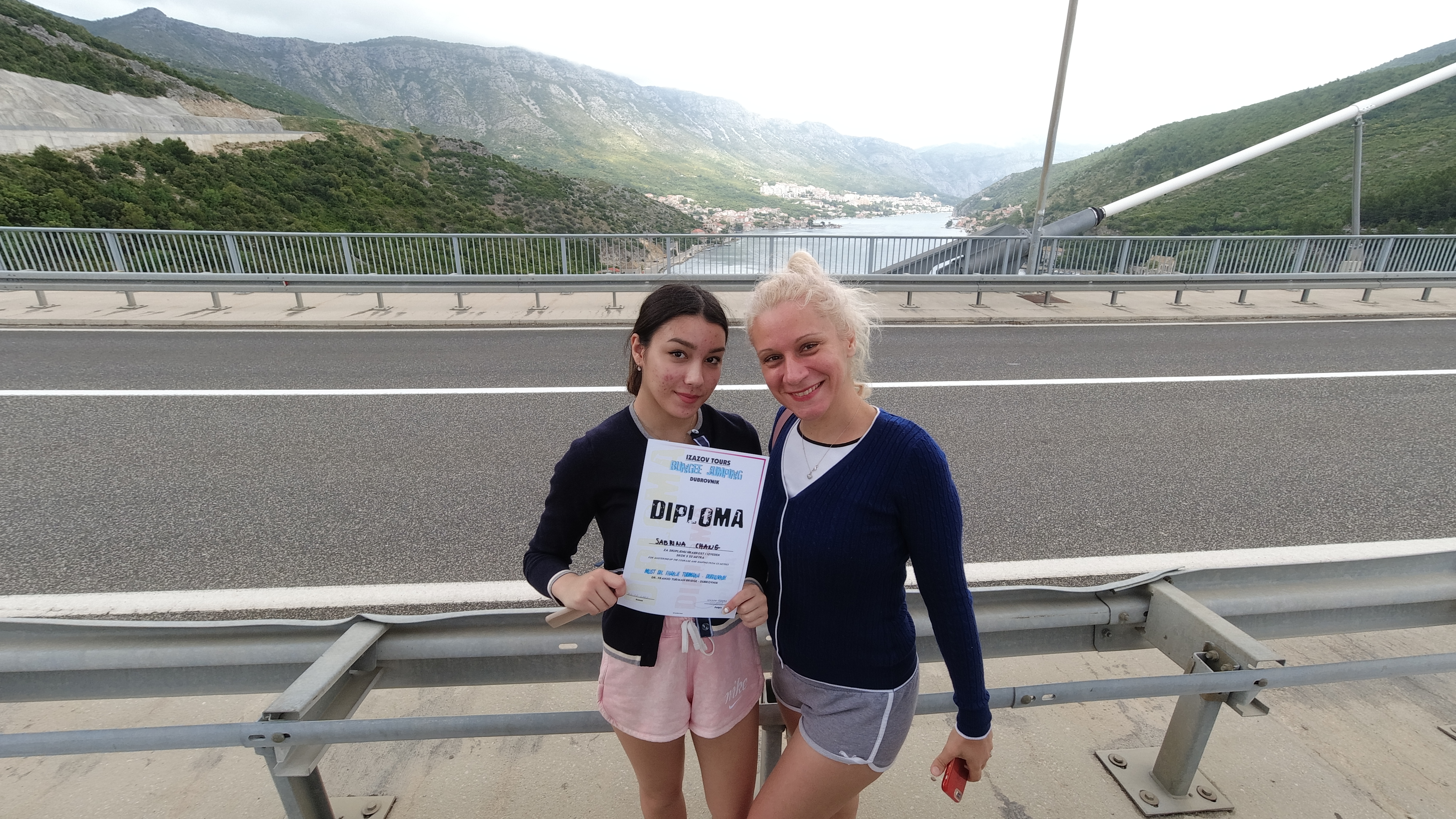 Two participants holding a Dubrovnik Bungee Jump diploma after completing their jump experience in Croatia