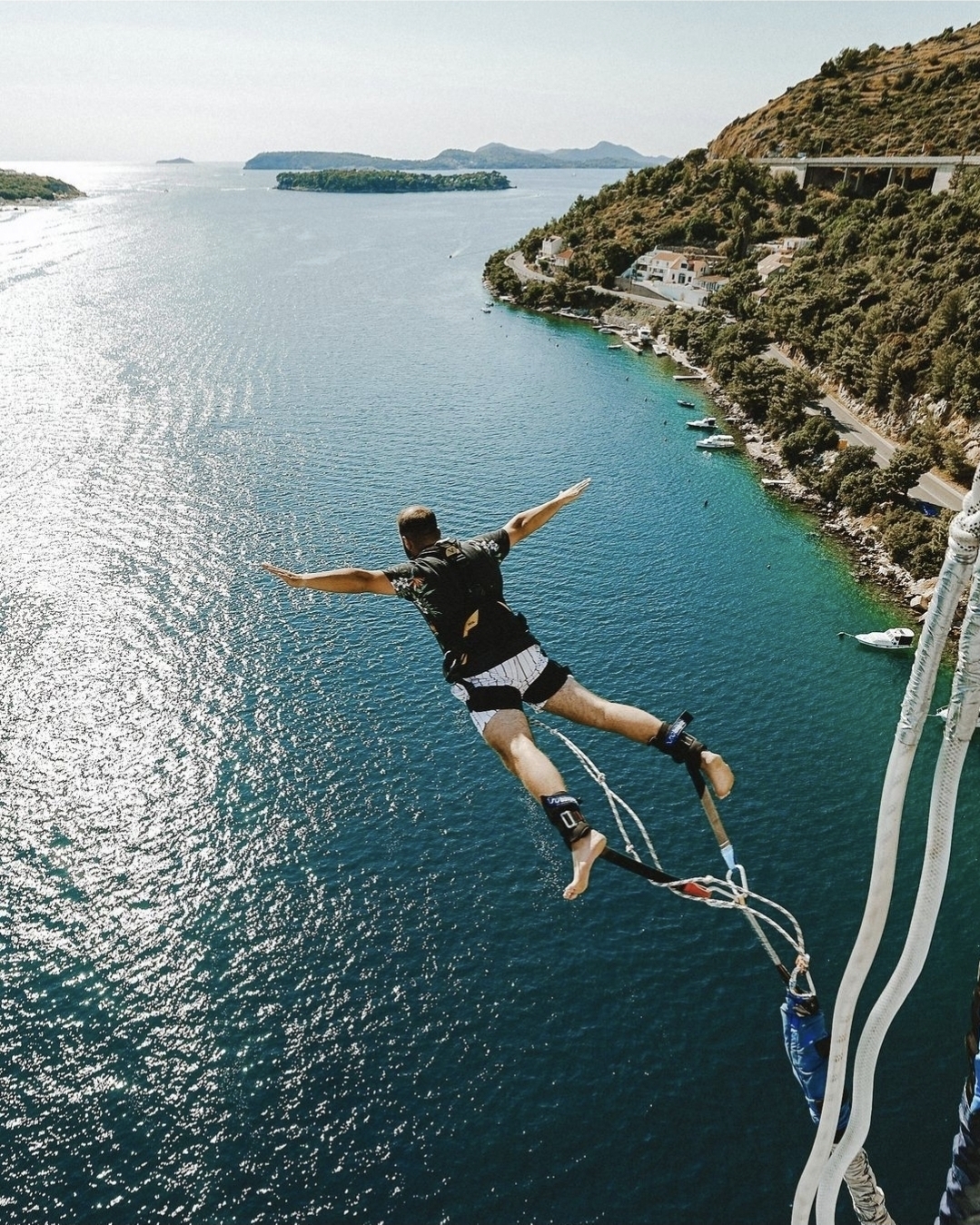 Participant performing a bungee jump in Dubrovnik with panoramic views of the Adriatic Sea and Croatian coastline